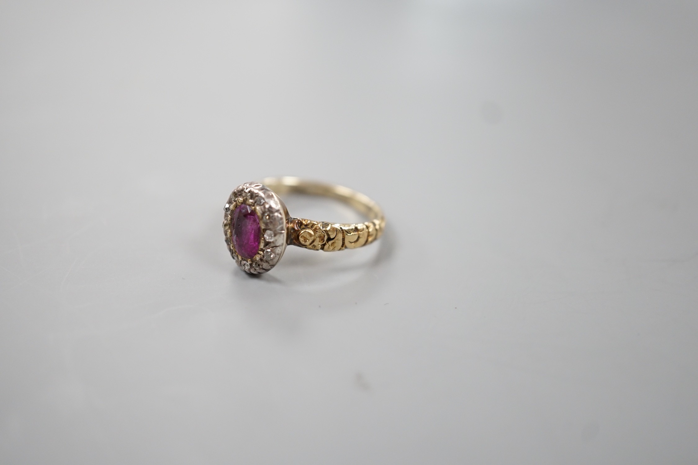 A 19th century yellow metal, garnet and diamond set oval cluster ring, size M, gross weight 2.2 grams.